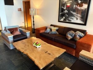 Eclectic lounge seating with an orange-brown sofa, uniquely patterned armchairs, and throw pillows.