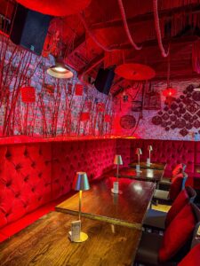 Red buttoned upholstered booth seating with wooden tables and warm lighting in a bespoke restaurant interior