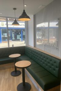 Modern bespoke green booth and banquette seating with round tables in a UK commercial space